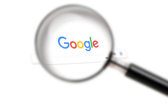 Google homepage of search on the screen under a magnifying glass. Google is world's most popular search engine. Moscow, Russia - October 26, 2018