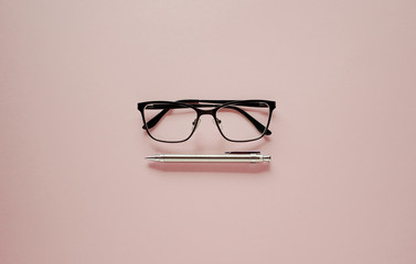 Office eyeglasses and pencil on pink background. Flat lay, top view