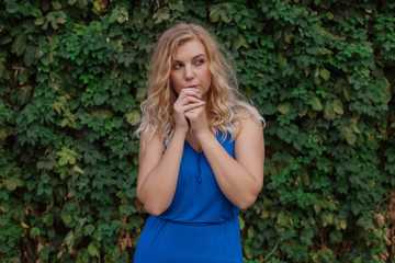 Frightened young beautiful girl on a background of a wall of wild grapes. Copy space.