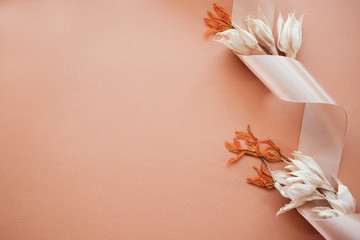 Feminine wedding desktop mockup with dry wildflowers and satin ribbon on coral background