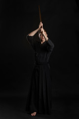 Kendo guru wearing in a traditional japanese kimono is practicing martial art with the shinai...
