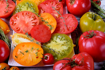 Red, orange, yellow and green tomatoes of different sorts. Assortment of sliced and whole tomatoes