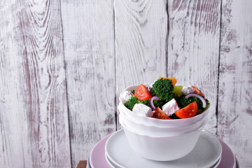 Light salad with broccoli, cherry tomatoes and feta cheese in a white ceramic bowl
