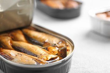 Tin can with sprats on light table, closeup. Space for text