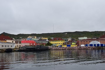 Fototapeta na wymiar view from the ocean towards a large empty pier along the ocean front colorful buildings in the background, Saint Pierre, Saint Pierre and Miquelon