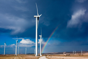 Camino a través de un parque eólico  hacia el inicio del arco iris