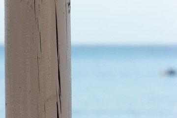 Poste de madera blanca de un chiringuito con mar de fondo