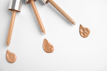 Samples of different foundation shades and droppers on white background, top view