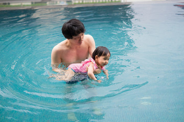 Father and baby girl swimming in a pool. infants swimming. Asian Baby swimming concept.
