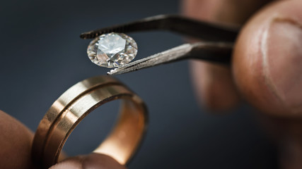 Jeweler craftsman selects a gem for a future gold ring, close-up
