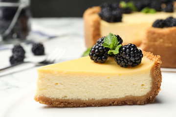 Piece of delicious cheesecake decorated with blackberries on table