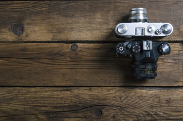 Old photo camera on wooden background, top view