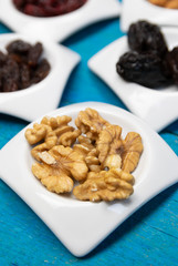 Food,taste and snack concept: walnuts in small white saucers on a wooden blue background.