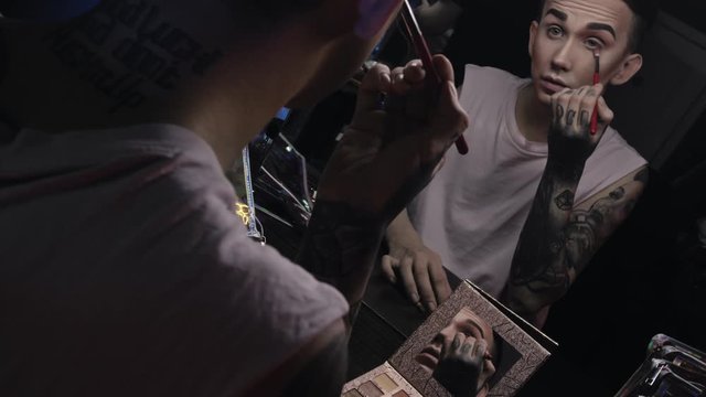 A travesty artist(transvestite) does makeup in the color dressing room before performing at a nightclub