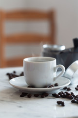 Hot cup of espresso or americano coffee in a traditional white cup on a table