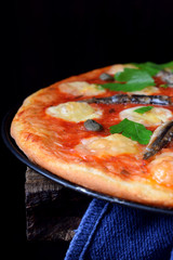 Round pizza with anchovies, capers, mozzarella and tomato sauce garnished with fresh parsley