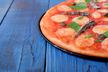 Round pizza with anchovies, capers, mozzarella cheese and tomato sauce garnished with fresh parsley