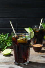 Glass of delicious cocktail with ice on table against dark wooden background