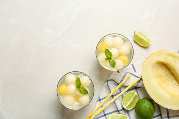 Glasses of melon ball cocktail with mint on light grey marble table, flat lay