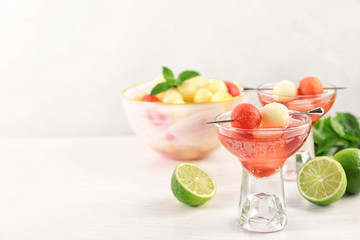 Glass of melon and watermelon ball cocktail on white wooden table. Space for text