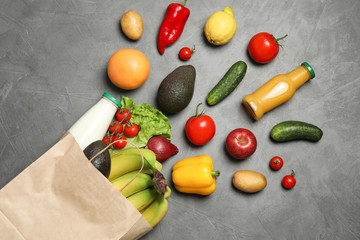 Paper bag with groceries on grey background, flat lay