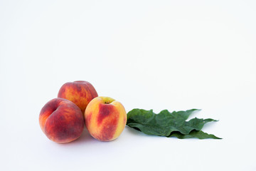 fresh peaches and green leaves on white background