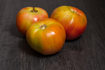 Several ecological tomatoes on a wooden table 