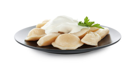 Delicious cooked dumplings with sour cream on white background