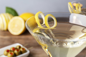 Glasses of lemon drop martini cocktail with zest on table against grey background