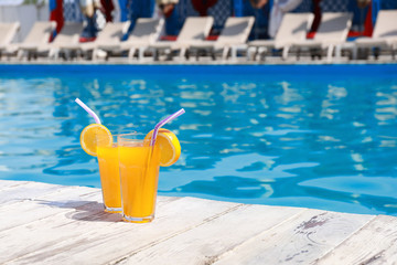 Refreshing cocktails near outdoor swimming pool on sunny day. Space for text
