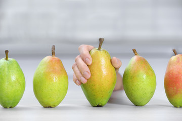 Woman taking fresh ripe pear from table in kitchen, closeup
