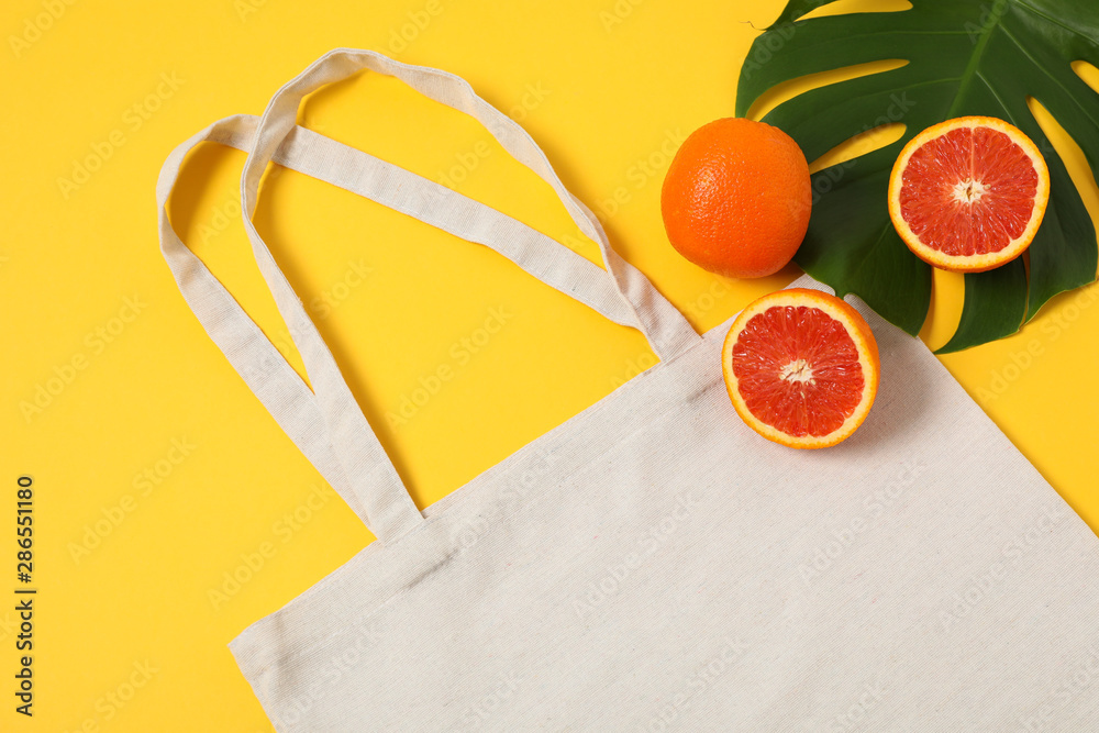 Wall mural Eco bag, palm leaf and orange on color background, copy space