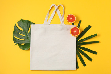 Eco bag, palm leaves and orange on color background, copy space
