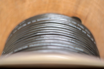 Wooden Coils of powerful black telecommunications wire. Many turns of the main electrical cable is closeup. Selective focus.  Roll of outdoor fiber optic signal shielded cables.
