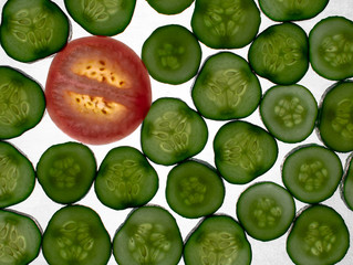 Beautiful, green, red, glowing slices of cucumber and tomato slice, lying on a white background. Cucumber and tomato slices, translucent flash.