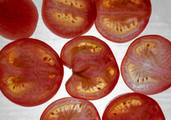 Beautiful, red, glowing tomato slices lying on a white background. Sliced tomatoes, educated flash.