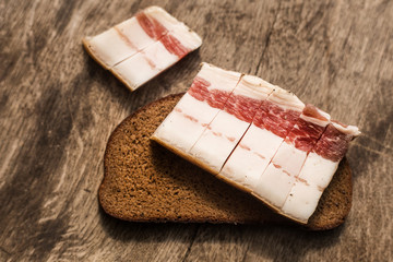 Bacon and bread and over wooden background. Russian and ukrainian traditional appetizer