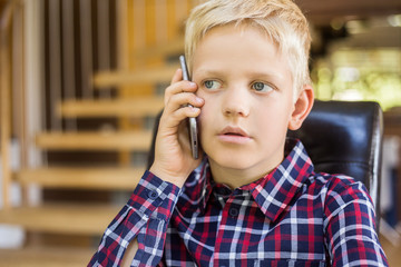 Cute little caucasian boy in a shirt talking on the phone. Modern concept. Technology