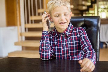 Cute little caucasian boy in a shirt talking on the phone. Modern concept. Technology