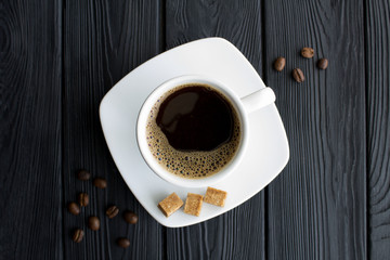 Black  coffee in the  white cup in the center of  the black wooden background. Top view. Copy space. Closeup.