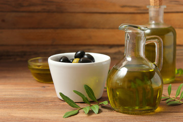 olive oil, green leaves and olives on the table.