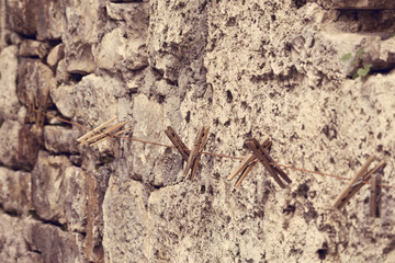 clothespins hanging on a lace against an old wall, home life, everyday life, Abstract ancient Stone Wall Background Image. Great for background use.