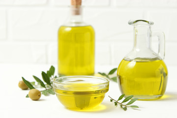 olive oil, green leaves and olives on the table.
