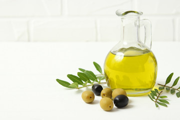 olive oil, green leaves and olives on the table.