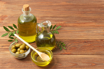 olive oil, green leaves and olives on the table.