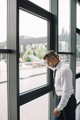 Fototapeta premium upset businessman in suit standing near windows in office