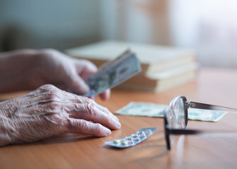 Money in the hands of an old woman. An elderly woman pensioner counts money. Elderly financial concept. Banknotes in the hands of an old woman.