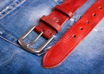 Red leather belt and blue jeans close-up. A belt lying on denim. Fashionable red belt close-up. 