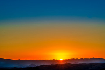 Fototapeta na wymiar Orange Sunrise over Silhouetted Mountains