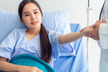 Fototapeta premium Asian young female patient lying in the bed improved symptoms allow the doctor to check and record the treatment results